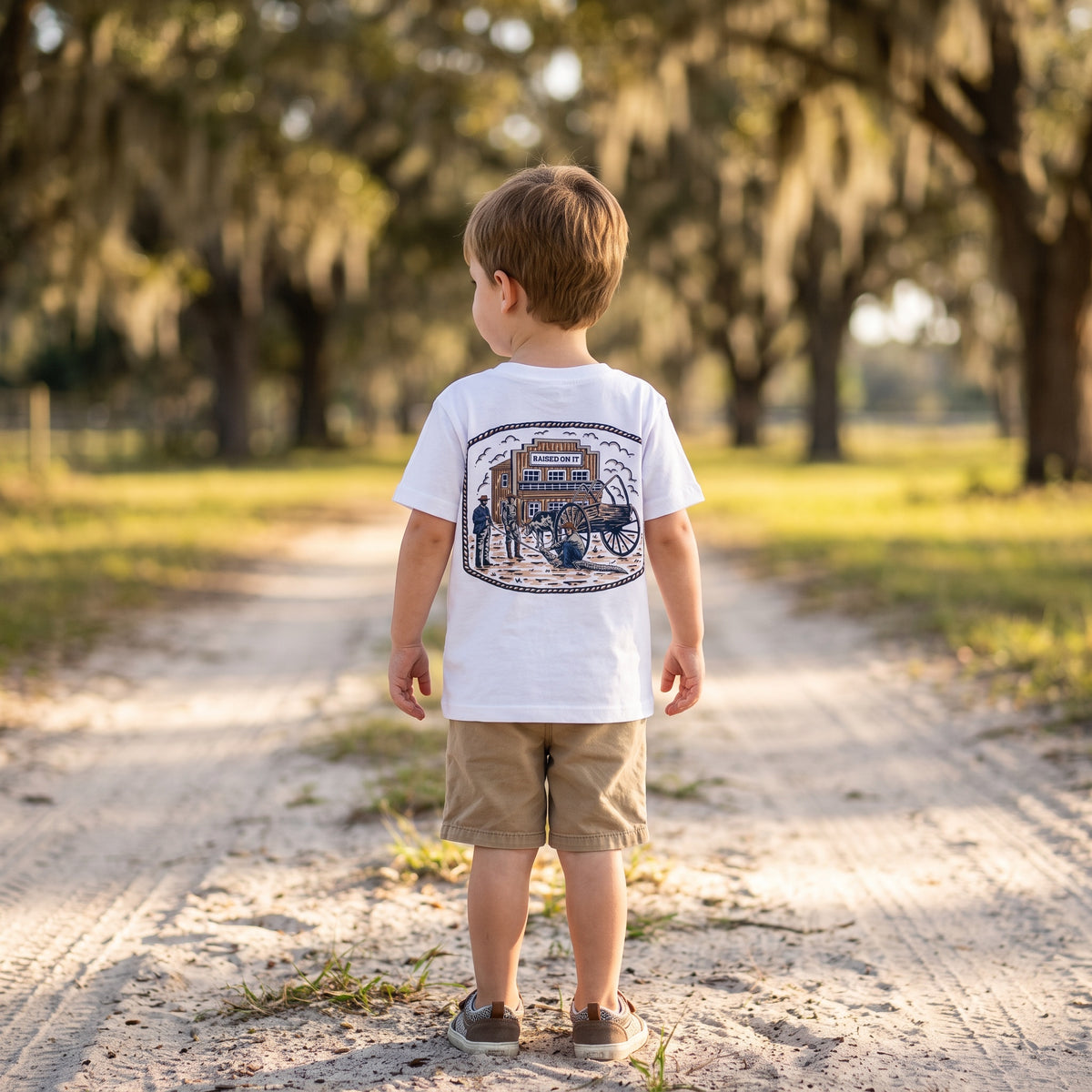 Toddler boy wearing the white Florida Cowboy Tee, back view of the full Raised On It ranch print